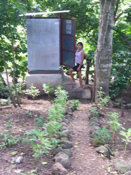 A girl showing her family's new outhouse.